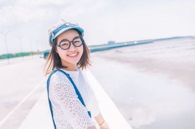 Portrait of smiling young woman standing at beach