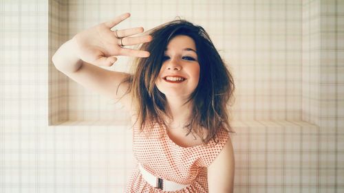 Portrait of smiling young woman holding camera at home