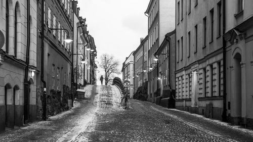 Rear view of woman walking on road along buildings