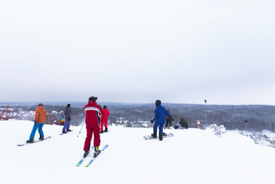 People on snow covered land against sky