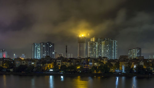 Illuminated buildings in city against sky at night