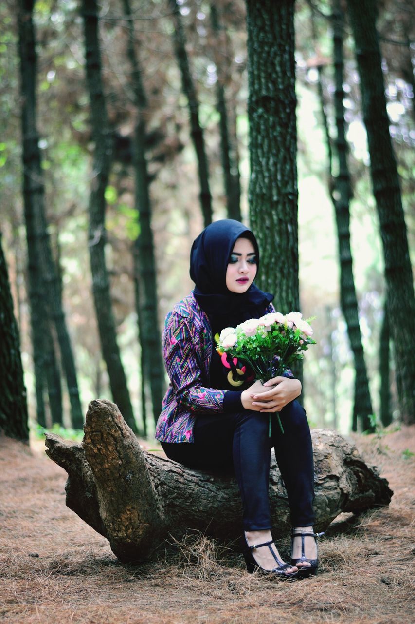 lifestyles, full length, casual clothing, leisure activity, tree, person, tree trunk, front view, standing, focus on foreground, holding, young women, young adult, warm clothing, forest, childhood, smiling, togetherness