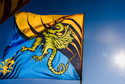 Low angle view of yellow flag against blue sky