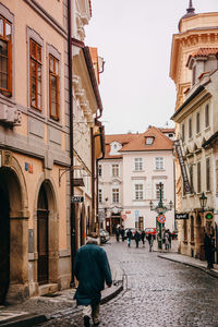 Rear view of people walking on street amidst buildings in city