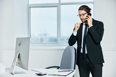 Young man using phone while sitting on table