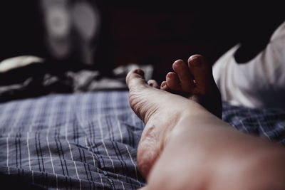 Low section of person relaxing on bed at home