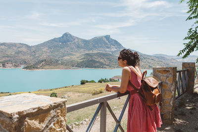 Rear view of woman standing by sea against sky