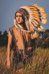 Young woman looking away while standing on field