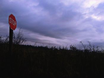 Road sign on field against sky