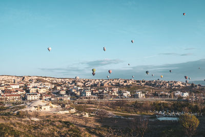 Hot air balloons flying over city against sky