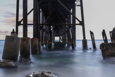 Panoramic view of wooden posts in sea against sky