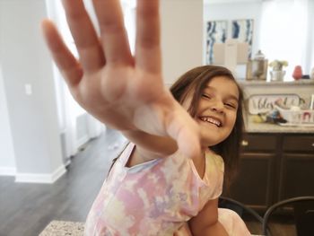 A young girl tries to grab the camera while laughing into the camera.