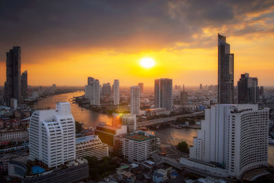 Modern buildings in city against sky during sunset chao phraya river.