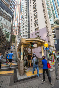 Rear view of people walking on street against modern buildings