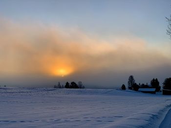 Scenic view of snow covered field against sky during sunset