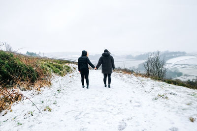 Rear view of women walking on snow covered landscape