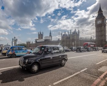 Cars on city street against sky