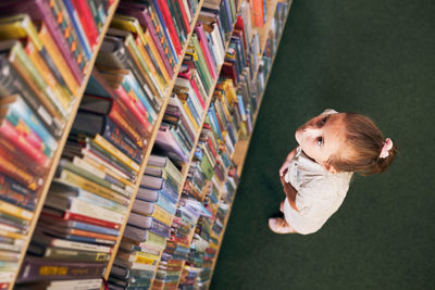 Full length of boy with books on shelf