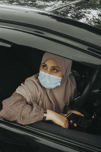 Portrait of young woman sitting in car