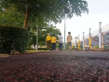 Surface level of people on footpath by road against sky