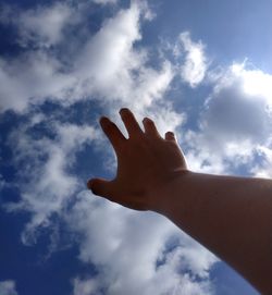 Low angle view of human hand against sky
