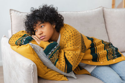 Portrait of young woman sitting on sofa at home