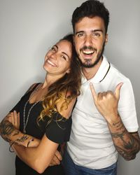Portrait of smiling young couple standing against white background