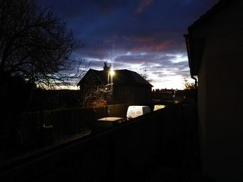 Silhouette houses against sky during sunset