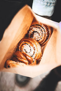 Cropped hand of person holding a bag full of cinnamon rolls 