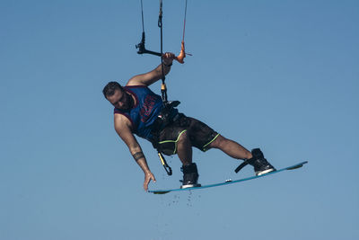 Low angle view of man kiteboarding against clear sky