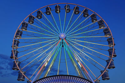 Low angle view of ferris wheel against blue sky