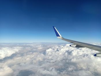 Airplane flying over cloudscape against blue sky