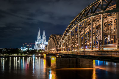 Illuminated bridge across river at night