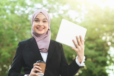Portrait of a smiling young woman holding camera