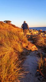 Rear view of man walking at beach during sunset