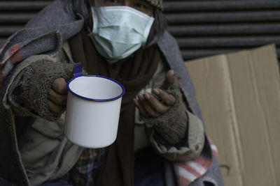 Beggar holding mug while begging