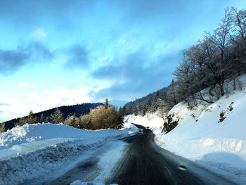 Road amidst snowcapped mountains against sky