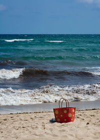 Deck chair on shore at beach against sky