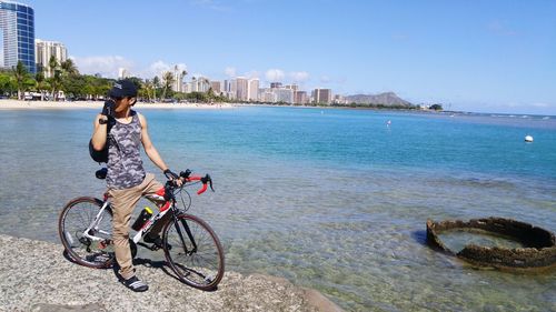 Young woman riding bicycle on beach in city
