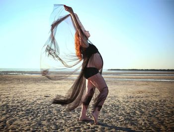 Pregnant woman standing at beach against sky