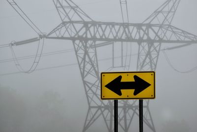 Low angle view of road sign on electricity pylon