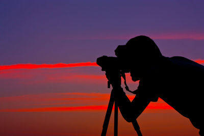 Silhouette man photographing against sky during sunset