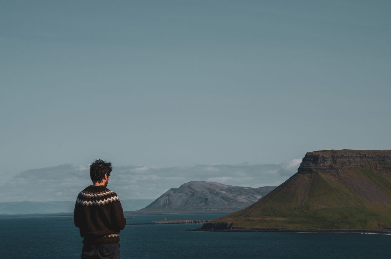 sky, mountain, one person, scenics - nature, rear view, beauty in nature, real people, leisure activity, water, lifestyles, standing, tranquil scene, nature, tranquility, non-urban scene, idyllic, copy space, day, mountain range, outdoors, looking at view