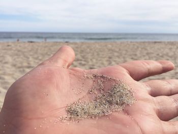 Cropped hand holding sand at beach