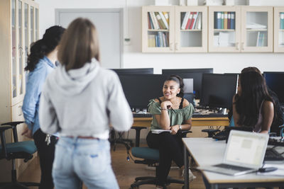 Smiling female high school students with teacher in computer lab