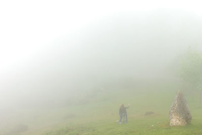 Rear view of person on landscape during foggy weather