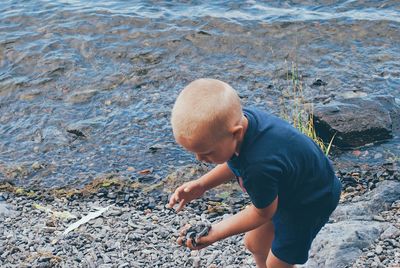 High angle view of boy on rock at shore