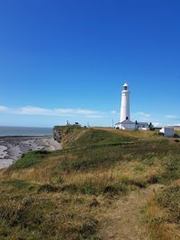 Lighthouse by sea against sky