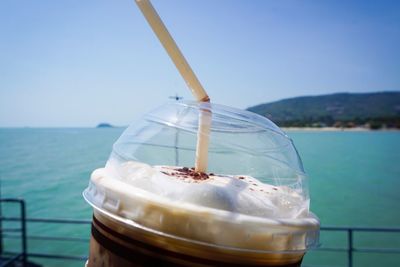 Close-up of drink in sea against sky