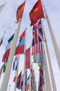 Low angle view of national flags waving against sky